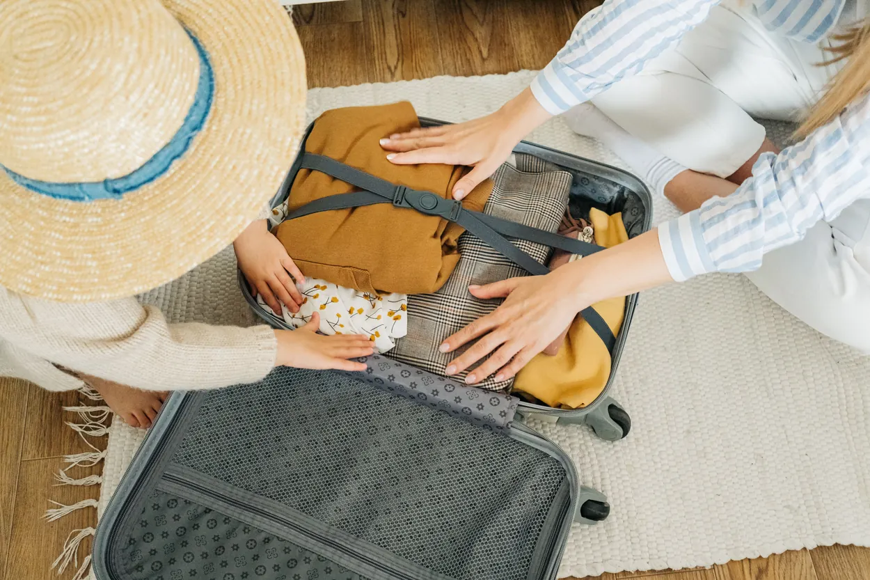 A traveler organizing clothing and other essentials in an open suitcase